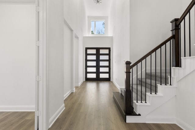 entryway with french doors, a towering ceiling, a chandelier, and hardwood / wood-style floors