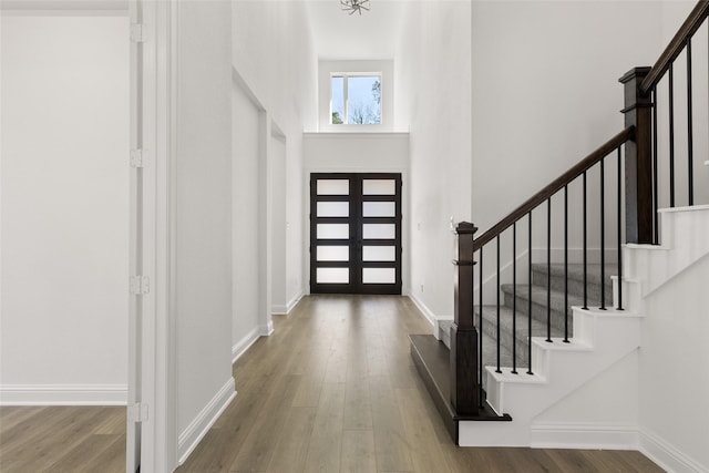 entryway featuring wood-type flooring, a towering ceiling, and french doors