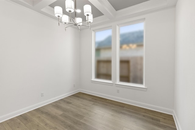 empty room with hardwood / wood-style flooring, an inviting chandelier, coffered ceiling, and beamed ceiling