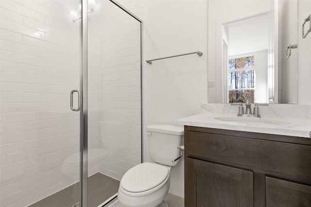 bathroom with toilet, vanity, and a shower with door