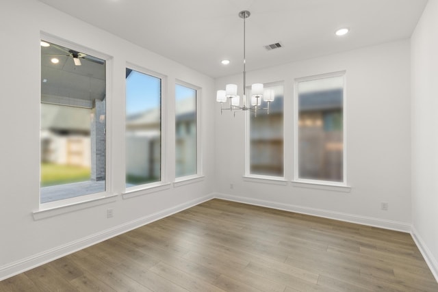 unfurnished dining area featuring hardwood / wood-style flooring and ceiling fan with notable chandelier