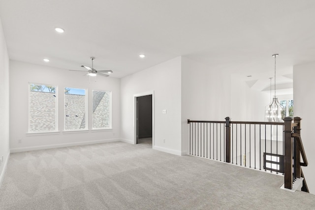 carpeted empty room featuring ceiling fan with notable chandelier