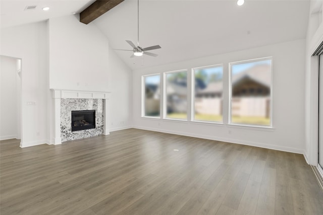 unfurnished living room with hardwood / wood-style flooring, ceiling fan, high vaulted ceiling, a high end fireplace, and beamed ceiling