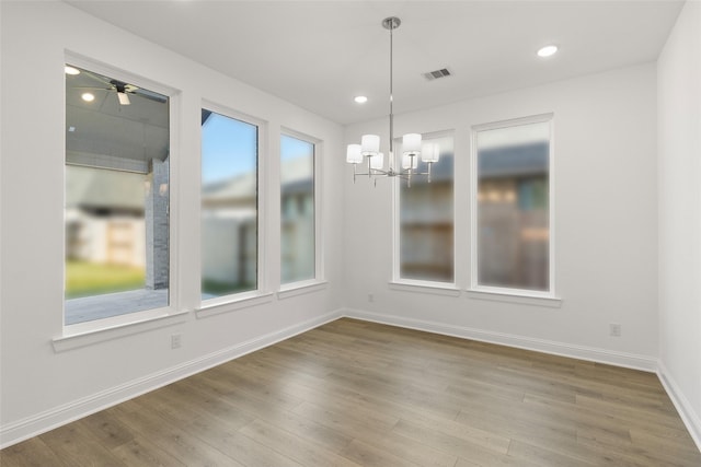 unfurnished dining area featuring hardwood / wood-style floors and an inviting chandelier