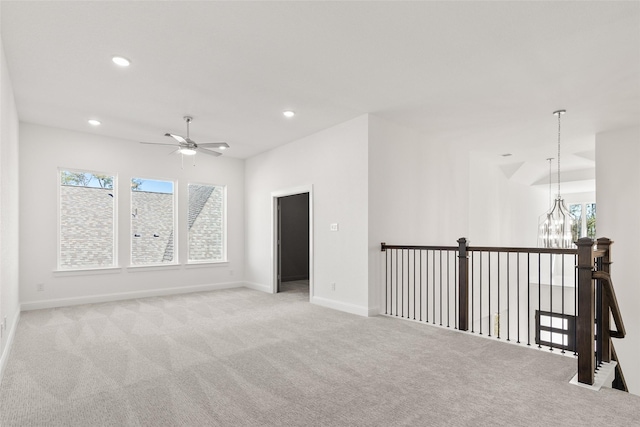 carpeted spare room featuring ceiling fan with notable chandelier