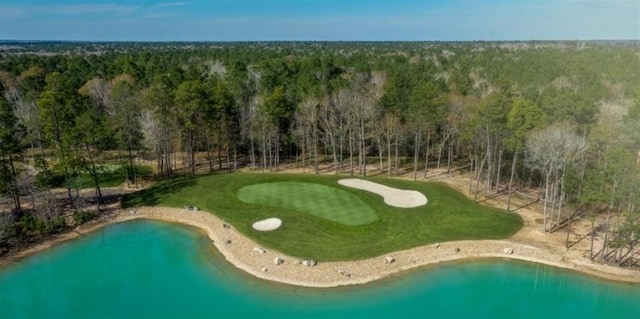 drone / aerial view with view of golf course, a water view, and a view of trees