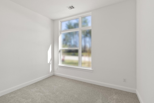 unfurnished room featuring visible vents, light carpet, and baseboards