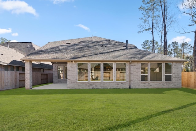 back of property featuring brick siding, a yard, a patio, a shingled roof, and a fenced backyard