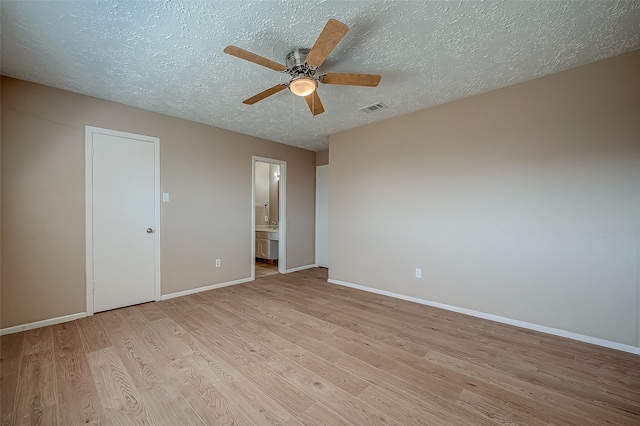 unfurnished bedroom with a textured ceiling, light hardwood / wood-style flooring, ensuite bath, and ceiling fan