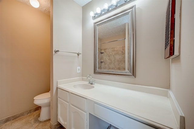 bathroom with tile patterned flooring, vanity, toilet, and a textured ceiling