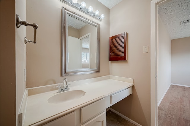 bathroom with hardwood / wood-style floors, vanity, and a textured ceiling