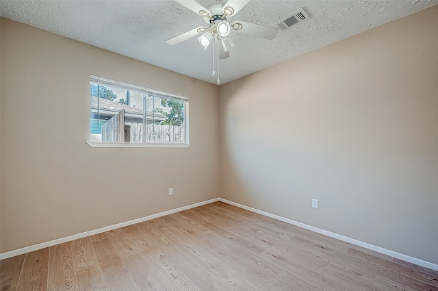 empty room with ceiling fan, light hardwood / wood-style flooring, and a textured ceiling