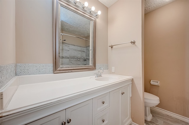 bathroom featuring a shower, a textured ceiling, toilet, vanity, and hardwood / wood-style flooring