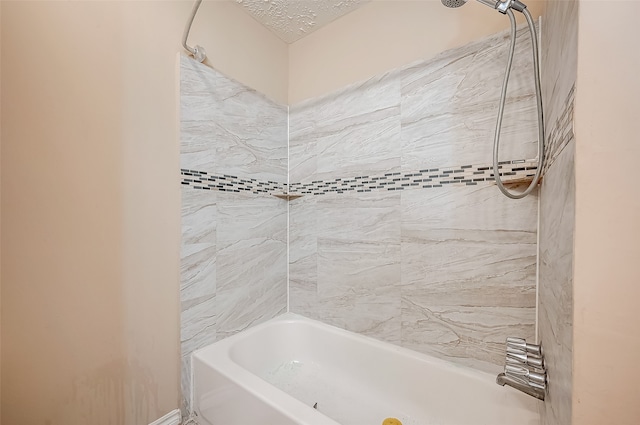 bathroom featuring a textured ceiling and tiled shower / bath