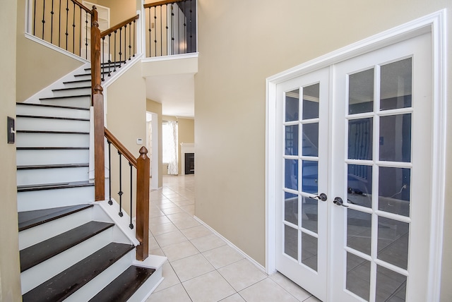 stairway featuring french doors, a high ceiling, and tile patterned flooring