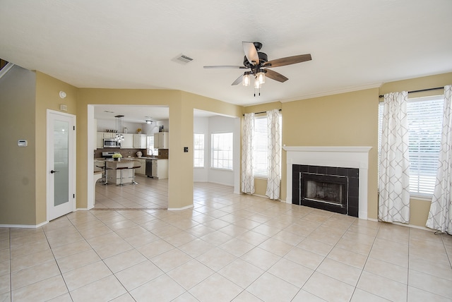 unfurnished living room featuring sink, a tiled fireplace, light tile patterned floors, and ceiling fan