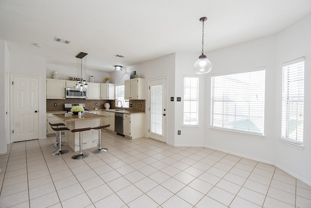 kitchen with tasteful backsplash, appliances with stainless steel finishes, a breakfast bar, pendant lighting, and sink