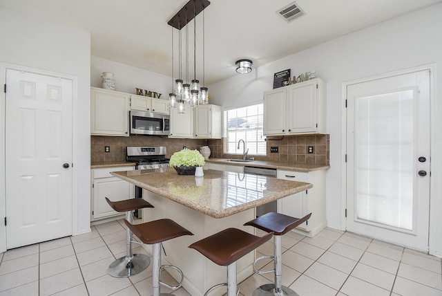 kitchen with white cabinetry, stainless steel appliances, sink, and a kitchen island