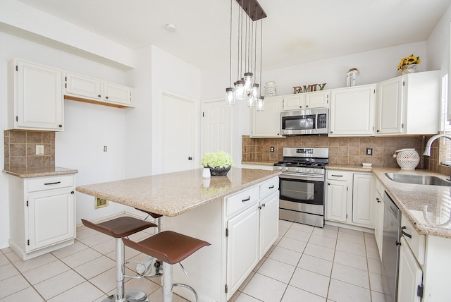 kitchen featuring sink, a kitchen island, white cabinets, and stainless steel appliances