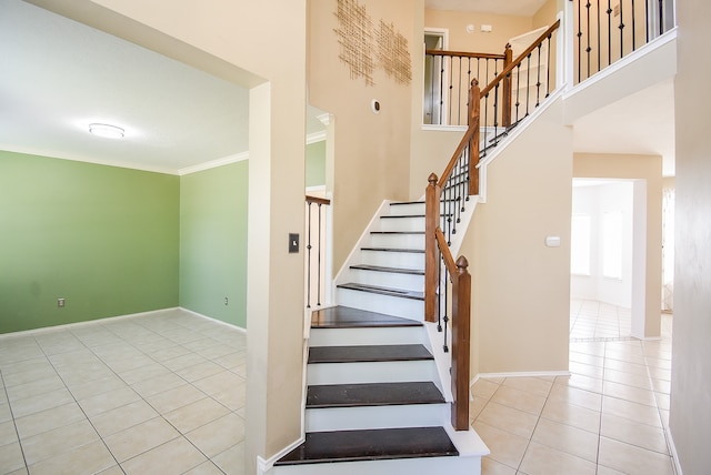 stairway featuring crown molding, a high ceiling, and tile patterned flooring