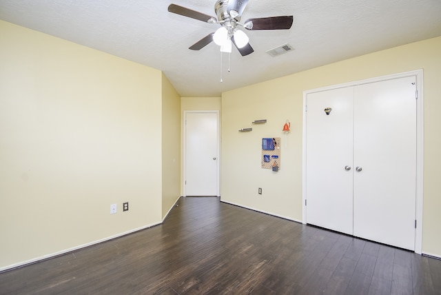 unfurnished bedroom featuring a closet, a textured ceiling, dark wood-type flooring, and ceiling fan