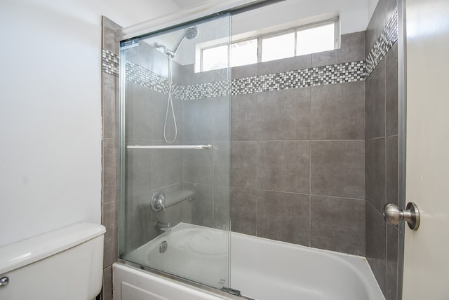 bathroom with toilet and combined bath / shower with glass door