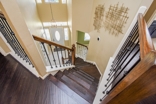 stairs with a high ceiling, a chandelier, and hardwood / wood-style floors