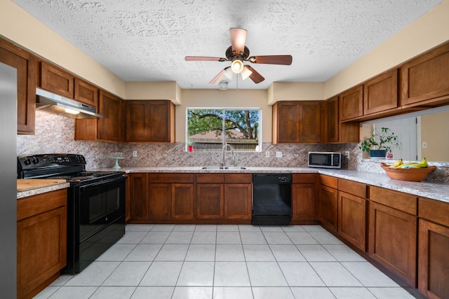 kitchen with light tile patterned flooring, tasteful backsplash, sink, black appliances, and a textured ceiling