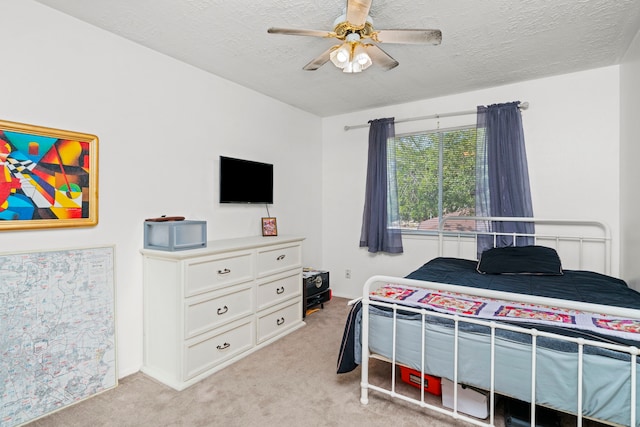 bedroom with a textured ceiling, ceiling fan, and light colored carpet