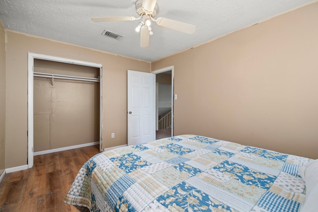 bedroom with a closet, dark hardwood / wood-style floors, a textured ceiling, and ceiling fan