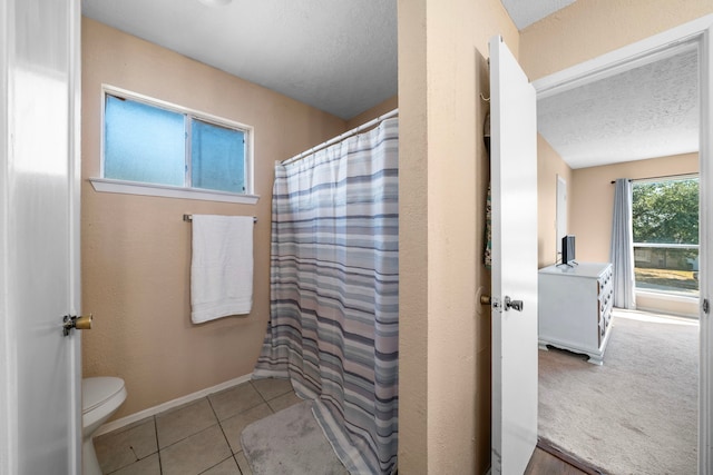 bathroom with a textured ceiling, tile patterned flooring, and toilet