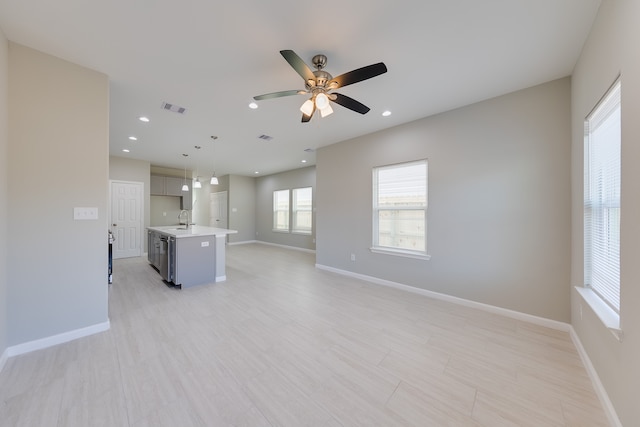 unfurnished living room with ceiling fan and sink