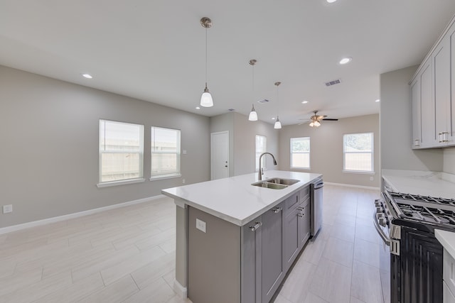 kitchen with gray cabinets, a center island with sink, sink, and light stone counters