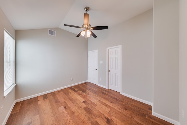 empty room with ceiling fan, lofted ceiling, hardwood / wood-style floors, and a wealth of natural light