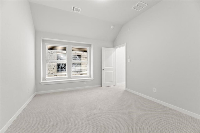 carpeted empty room featuring vaulted ceiling