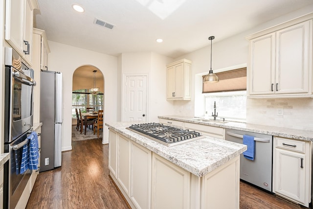 kitchen featuring dark wood-type flooring, sink, decorative light fixtures, a kitchen island, and stainless steel appliances