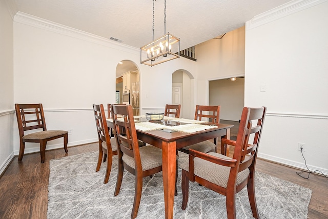 dining space with ornamental molding, dark wood-type flooring, and an inviting chandelier