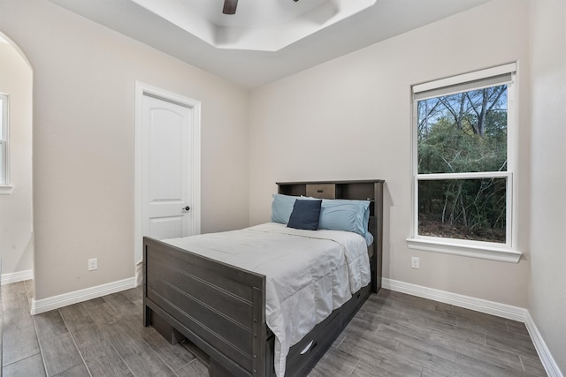 bedroom with a raised ceiling, hardwood / wood-style flooring, and ceiling fan