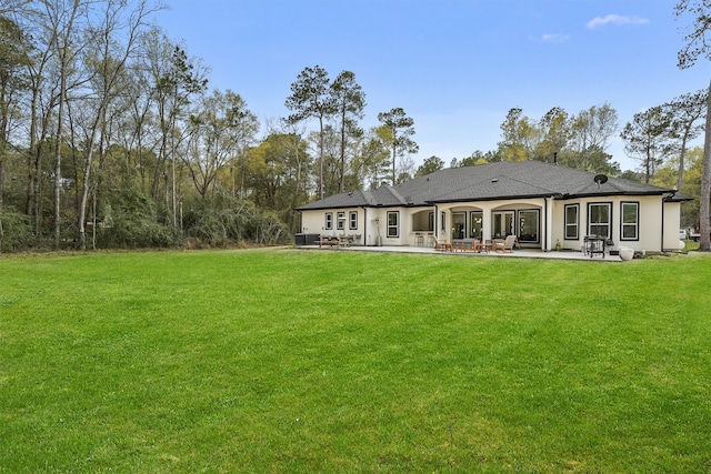 back of property with a yard and a patio