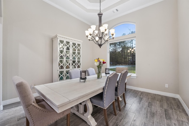 dining area featuring a raised ceiling, crown molding, hardwood / wood-style floors, and a chandelier