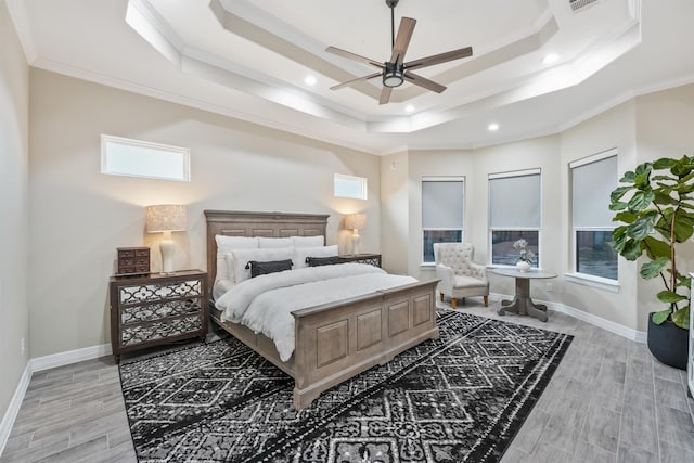 bedroom with ornamental molding, light wood-type flooring, ceiling fan, and a raised ceiling