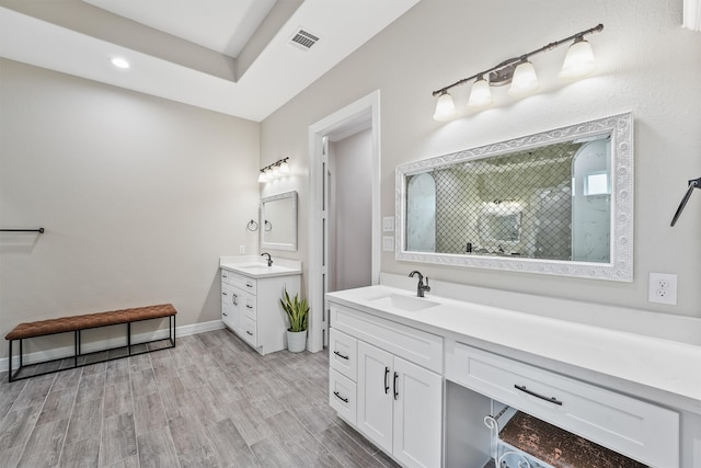 bathroom with walk in shower, vanity, and hardwood / wood-style floors