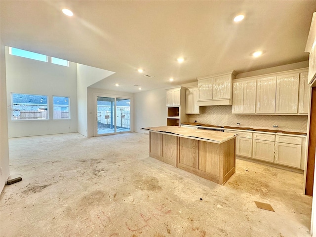 kitchen featuring decorative backsplash, a healthy amount of sunlight, and an island with sink