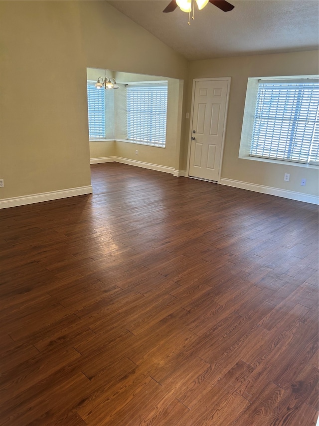 unfurnished room featuring ceiling fan with notable chandelier, lofted ceiling, dark hardwood / wood-style floors, and a textured ceiling