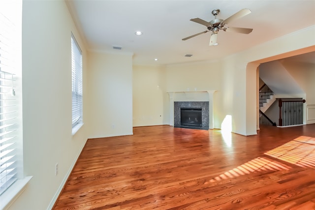 unfurnished living room with a premium fireplace, ornamental molding, hardwood / wood-style flooring, and ceiling fan