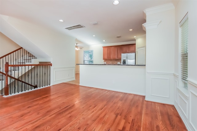 kitchen with decorative backsplash, dark stone counters, stainless steel fridge, light wood-type flooring, and ceiling fan