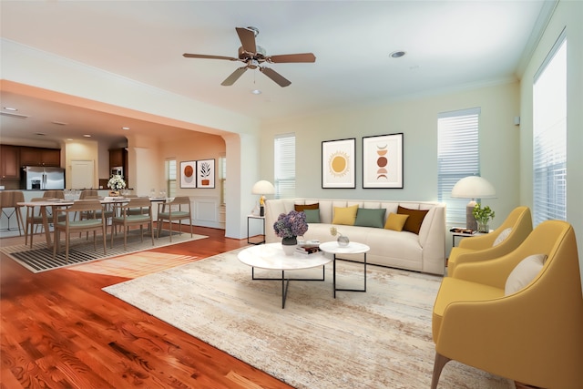 living room featuring ornamental molding, light wood-type flooring, and ceiling fan