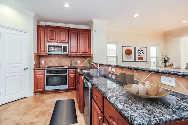 kitchen with appliances with stainless steel finishes, a wealth of natural light, dark stone counters, and ornamental molding