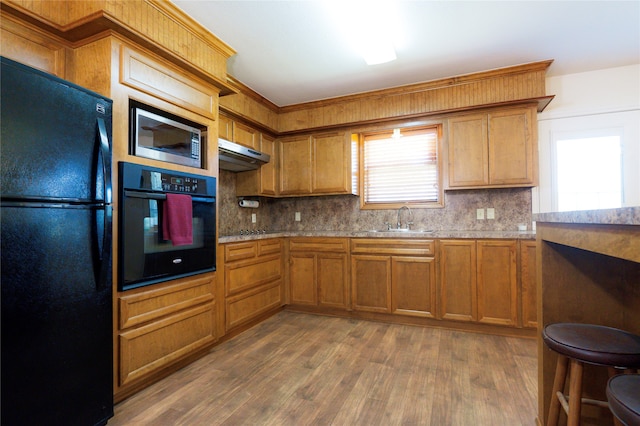 kitchen featuring sink, black appliances, dark wood-type flooring, and tasteful backsplash