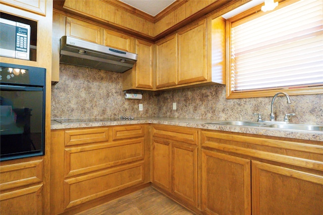 kitchen featuring backsplash, hardwood / wood-style flooring, ornamental molding, black appliances, and sink